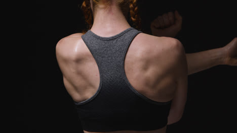 Close-Up-Studio-Shot-Showing-Back-Of-Mature-Woman-Wearing-Gym-Fitness-Clothing-Doing-Stretching-Exercises